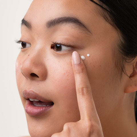 Model applying Early Riser Eye Cream to under eye area